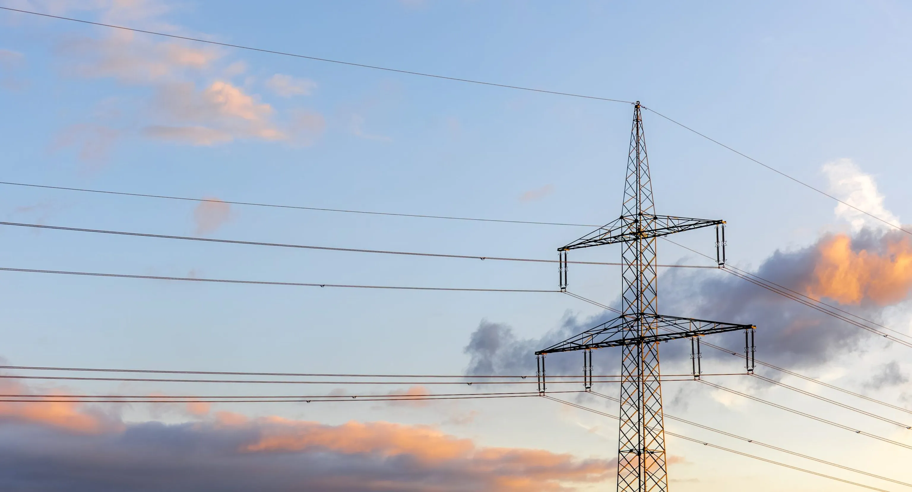 Vue plongeante sur une ligne haute tension avec un coucher de soleil derrière